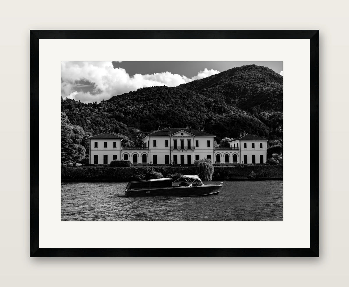 end game, black and white photograph of a lakeside villa and wooden motorboat, A2 print in a black wood gallery frame with an even museum mat